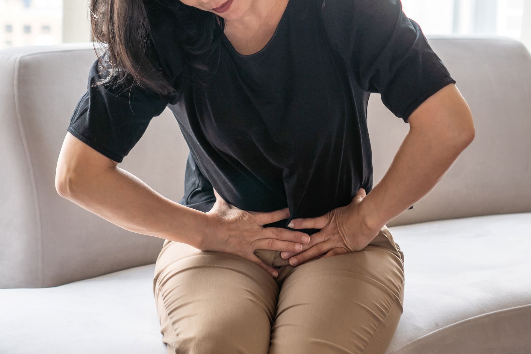 Woman sitting on couch with pelvic pain